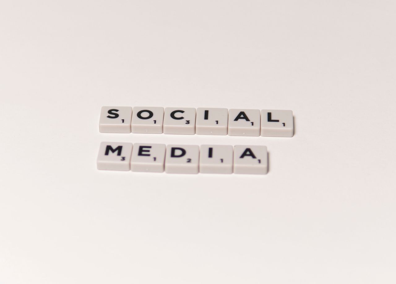 Des lettres de Scrabble formant social media sur un fond blanc, illustrant les notions de communication numérique.