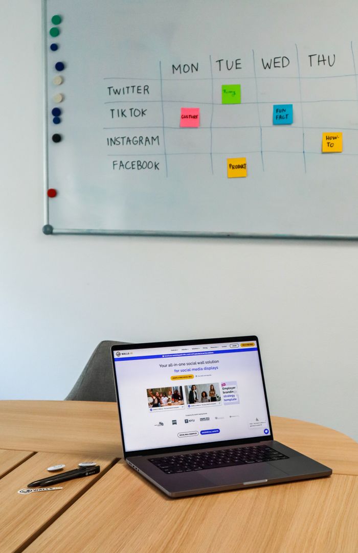 Un espace de travail moderne avec un ordinateur portable et un planning sur tableau blanc pour les plateformes de réseaux sociaux.